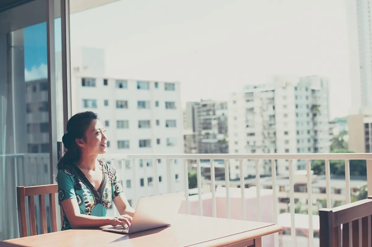 Une femme consulte son ordinateur sur une terrasse.