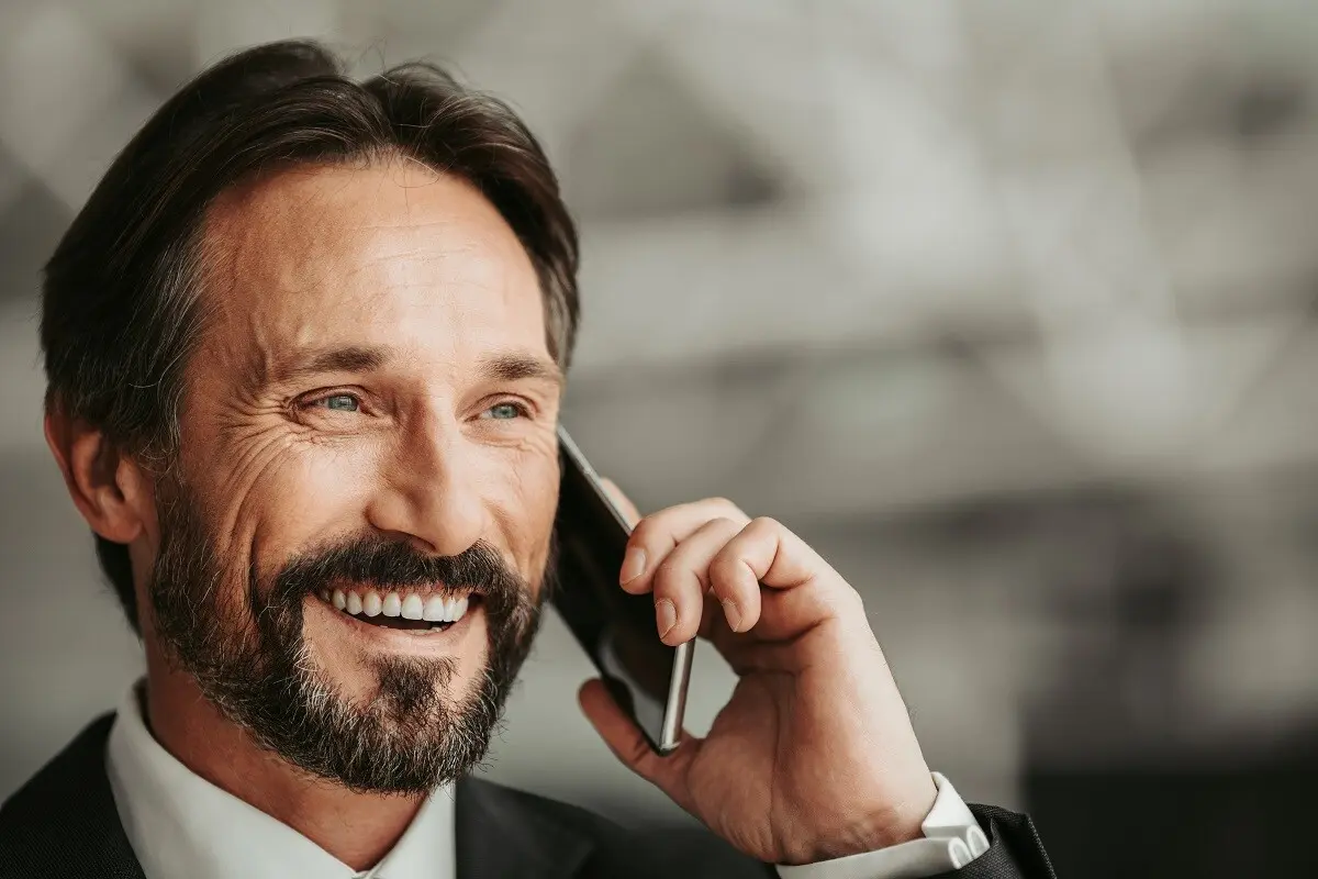 Un homme sourit et est au téléphone.